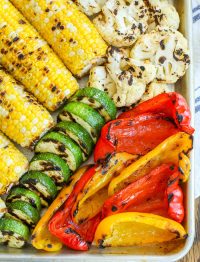 close up of grilled bell peppers, corn, and squash on tray