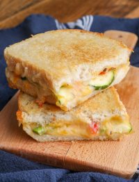 roasted vegetables in a grilled cheese sandwich on board with towel under it