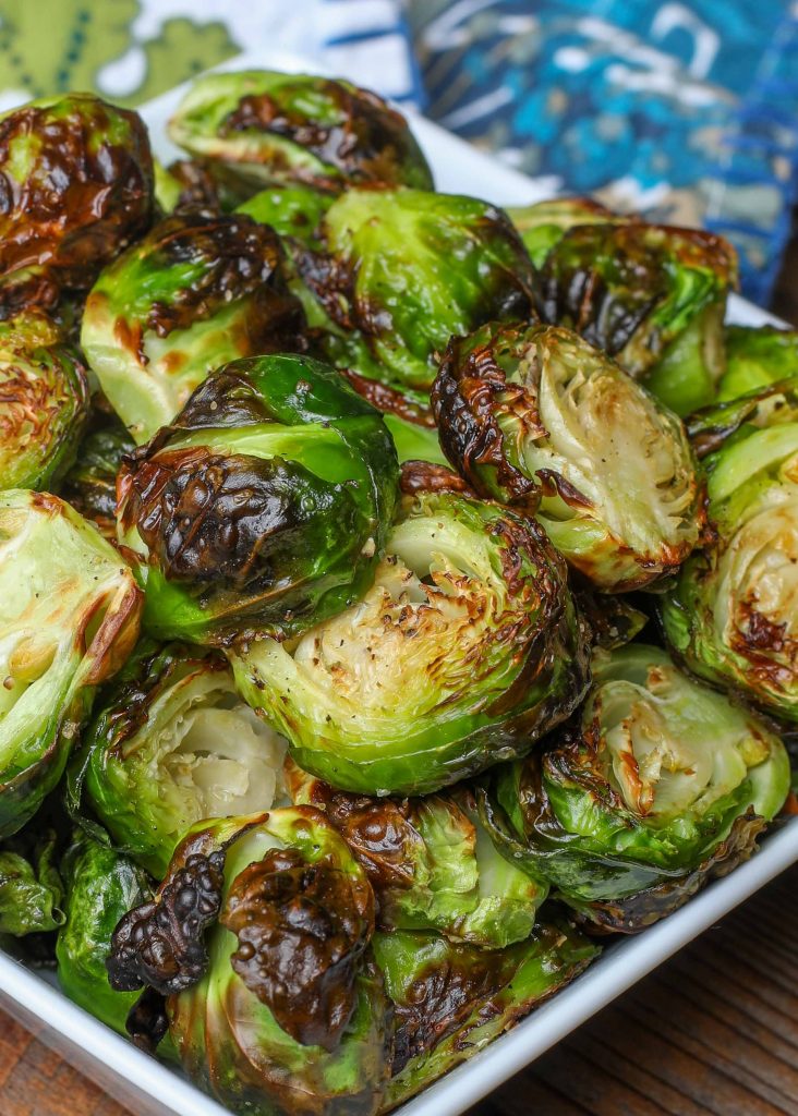 Air fried Brussels sprouts in a square white bowl with blue napkin