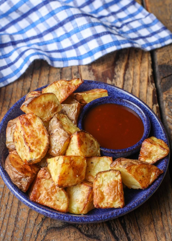 Crispy potatoes in bowl bowl with bbq sauce for dipping