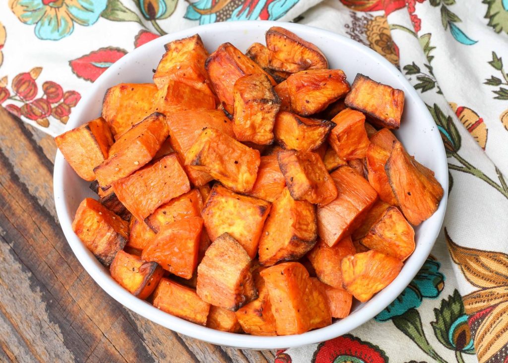 cooked sweet potatoes in white bowl with flowered napkin