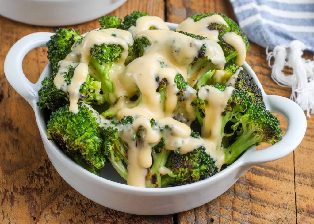 broccoli with cheese sauce in round white dish