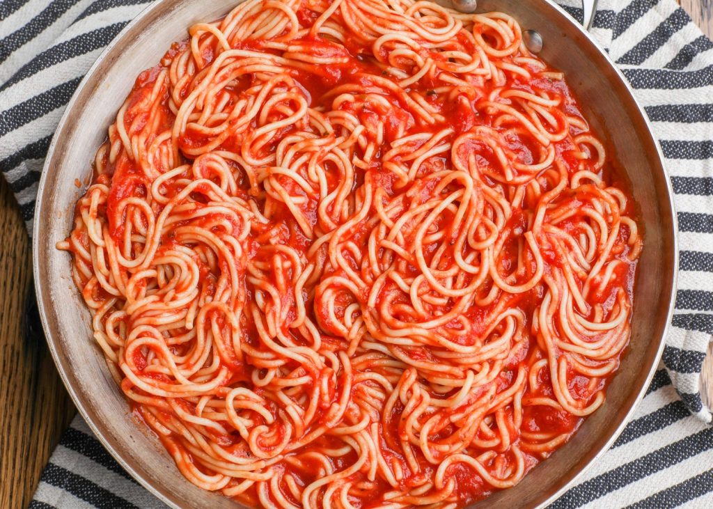 spaghetti with red sauce in pan with stripe napkin
