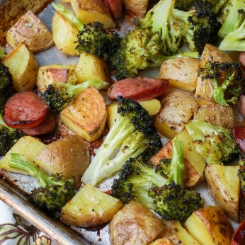 Broccoli, potatoes, and sausage roasting on sheet pan