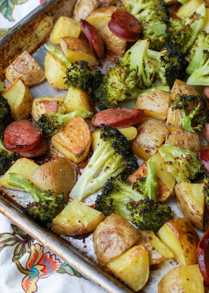 Broccoli, potatoes, and sausage roasting on sheet pan
