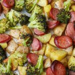 Bite-size potatoes, smoked sausage chunks, and broccoli florets on sheet pan
