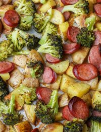 Bite-size potatoes, smoked sausage chunks, and broccoli florets on sheet pan