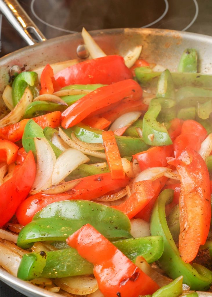 bell peppers and onions sauteed in large skillet on stove