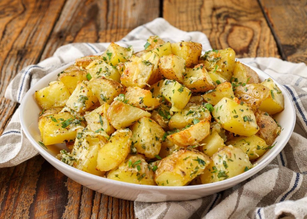 roasted potatoes in white serving dish with floral towel