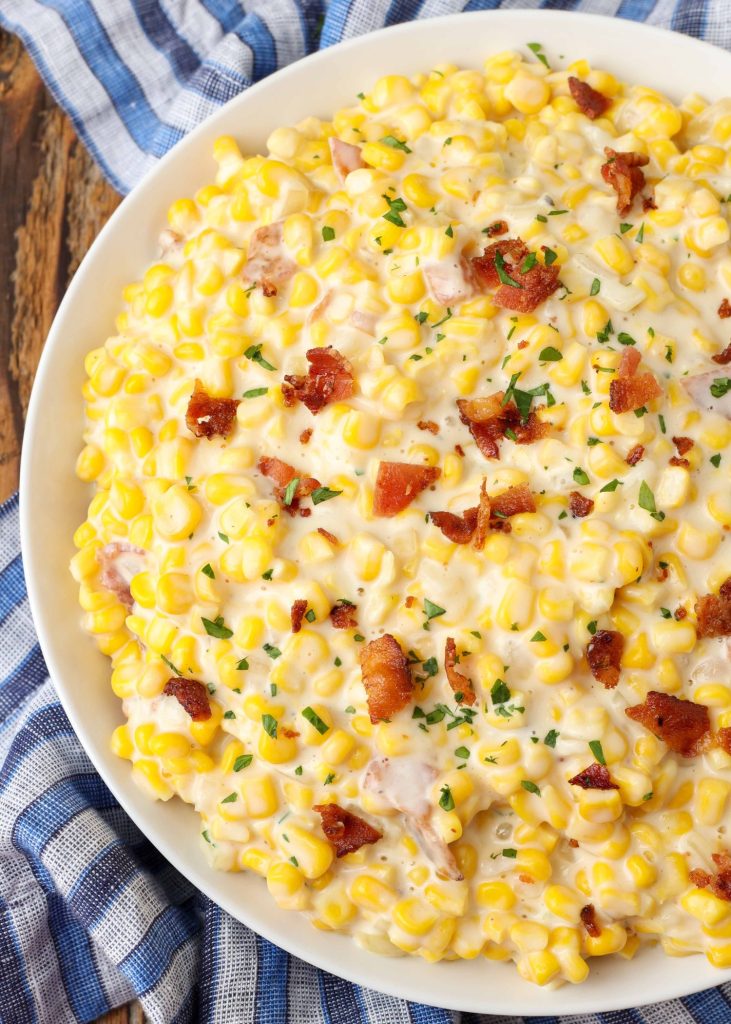 Creamed Corn with Bacon in white bowl on blue checkered towel