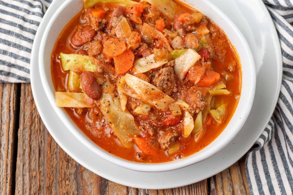 Soup with vegetables, ground beef, and Italian spices in white pottery bowl