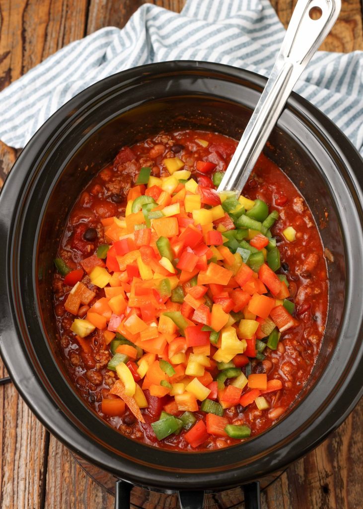 chili with bell peppers in crockpot with metal spoon