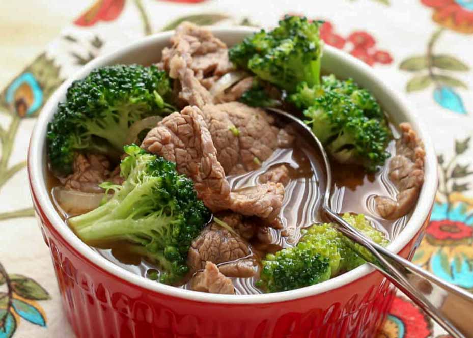 soup with beef and broccoli in small red bowl
