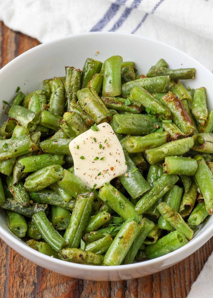 Air Fryer Frozen Green Beans in white bowl with butter