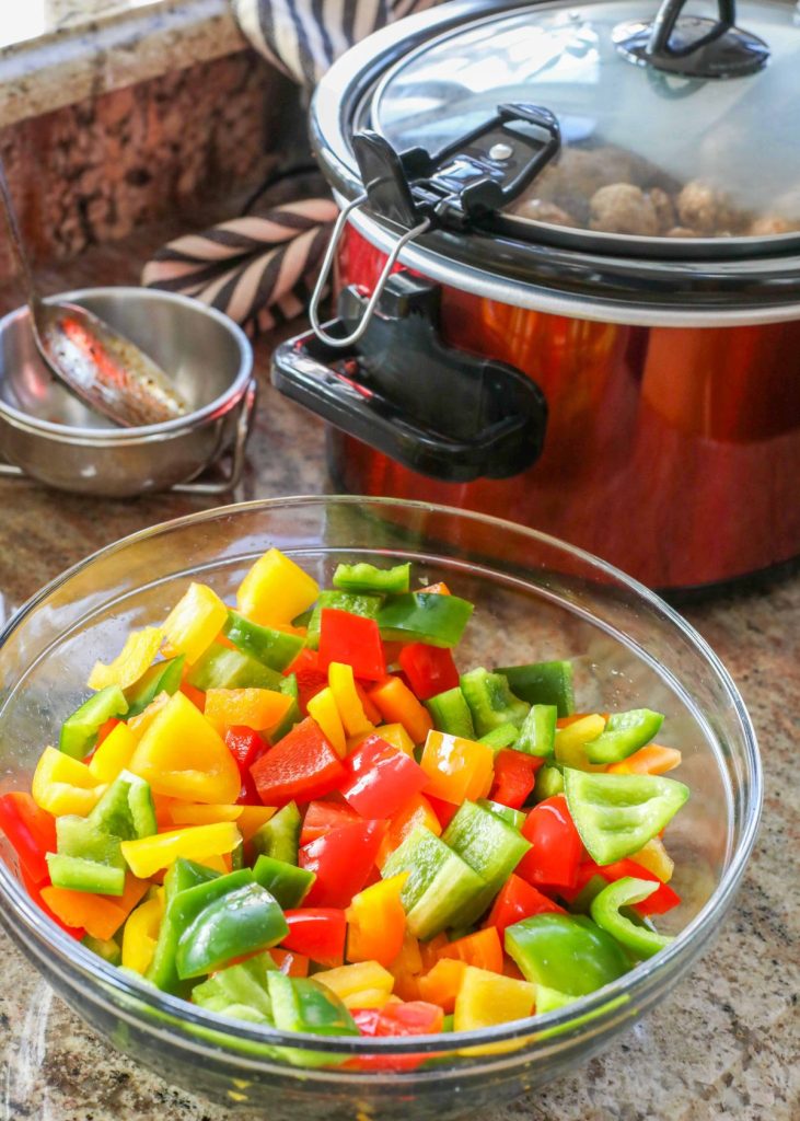 chopped bell peppers in bowl next to crockpot