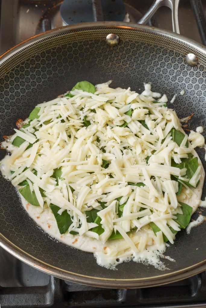 Spinach Quesadilla with umelted cheese in skillet