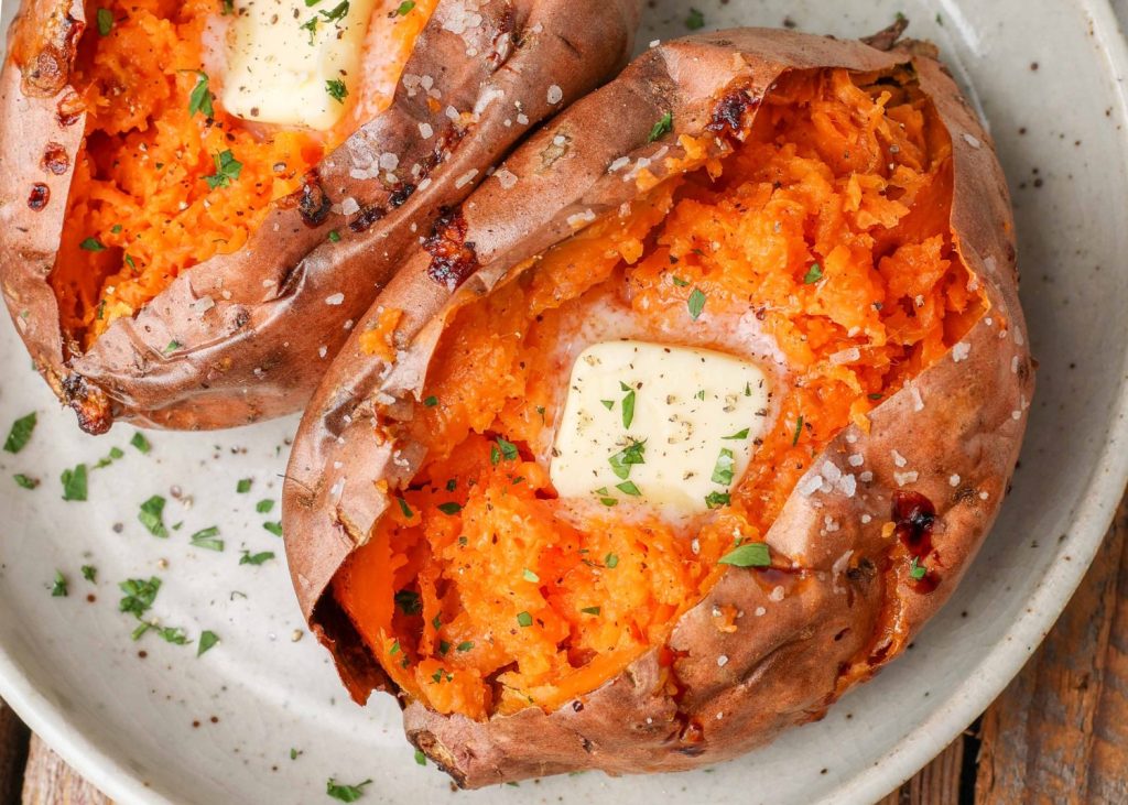 Air Fryer Baked Sweet Potatoes on a white plate topped with butter