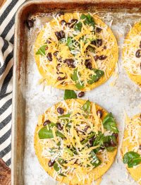tostada shells layered with cheese, black beans, and spinach before baking