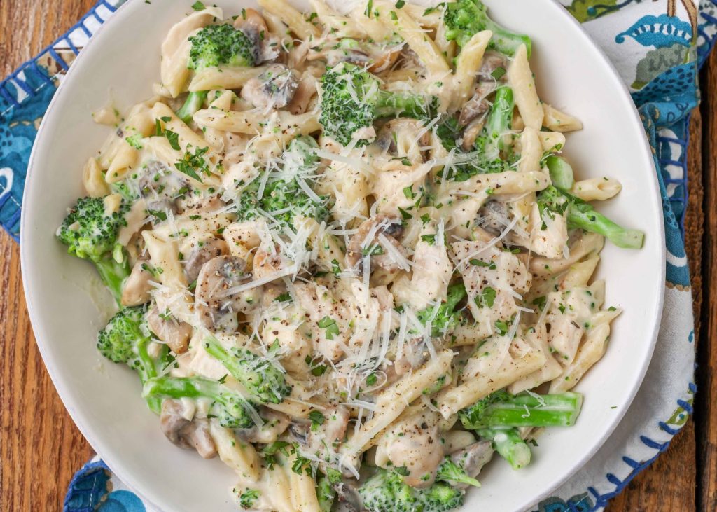 Mushroom Broccoli Pasta in white dish with blue flowered cloth.