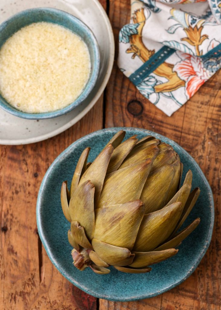 artichoke with dipping sauce on pottery plates