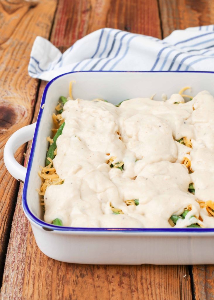 cream sauce and cheese over green beans in baking dish