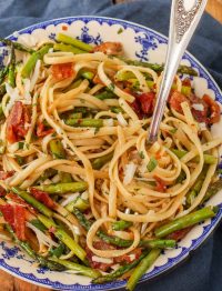 pasta with asparagus and bacon in blue and white bowl with fork