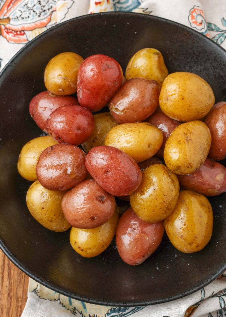 red and yellow boiled potatoes in black bowl