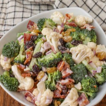 Broccoli Cauliflower Salad in white bowl with blue and white linen