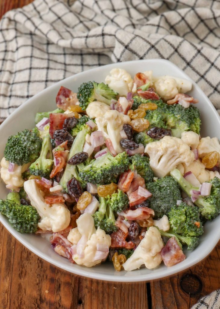 Broccoli Cauliflower Salad in white bowl with blue and white linen