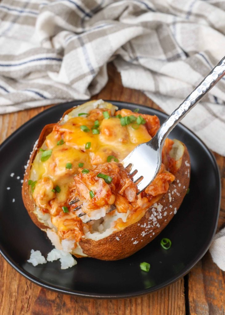 Chicken Stuffed Potatoes on black plate with a fork