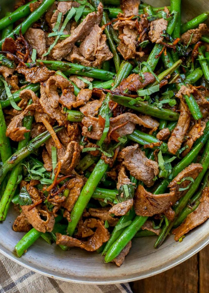 close up of green beans with thinly sliced steak in skillet