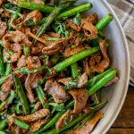 Stir fried steak and green beans in skillet with grey tea towel