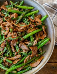 Stir fried steak and green beans in skillet with grey tea towel