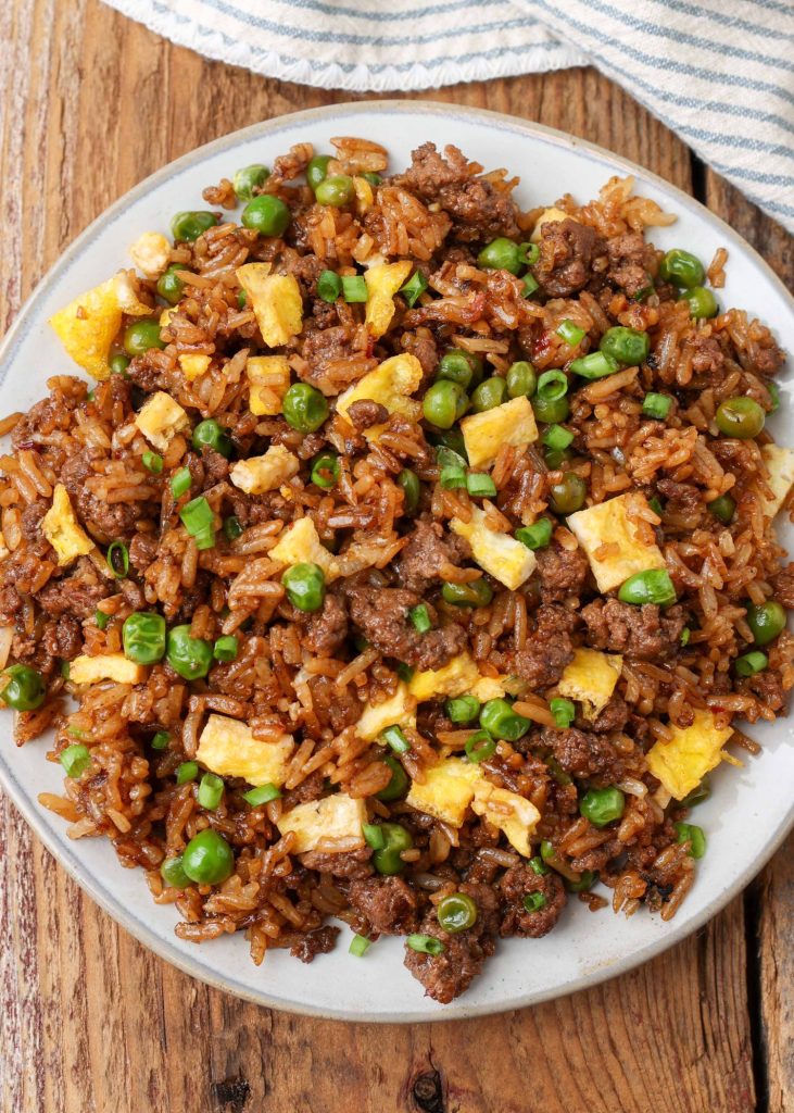 rice with ground beef and peas on white plate with striped napkin