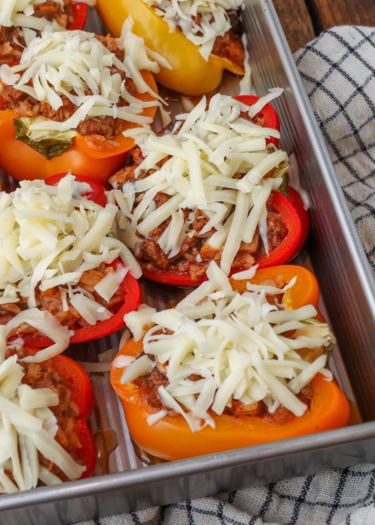 cheese topped stuffed peppers ready for the oven