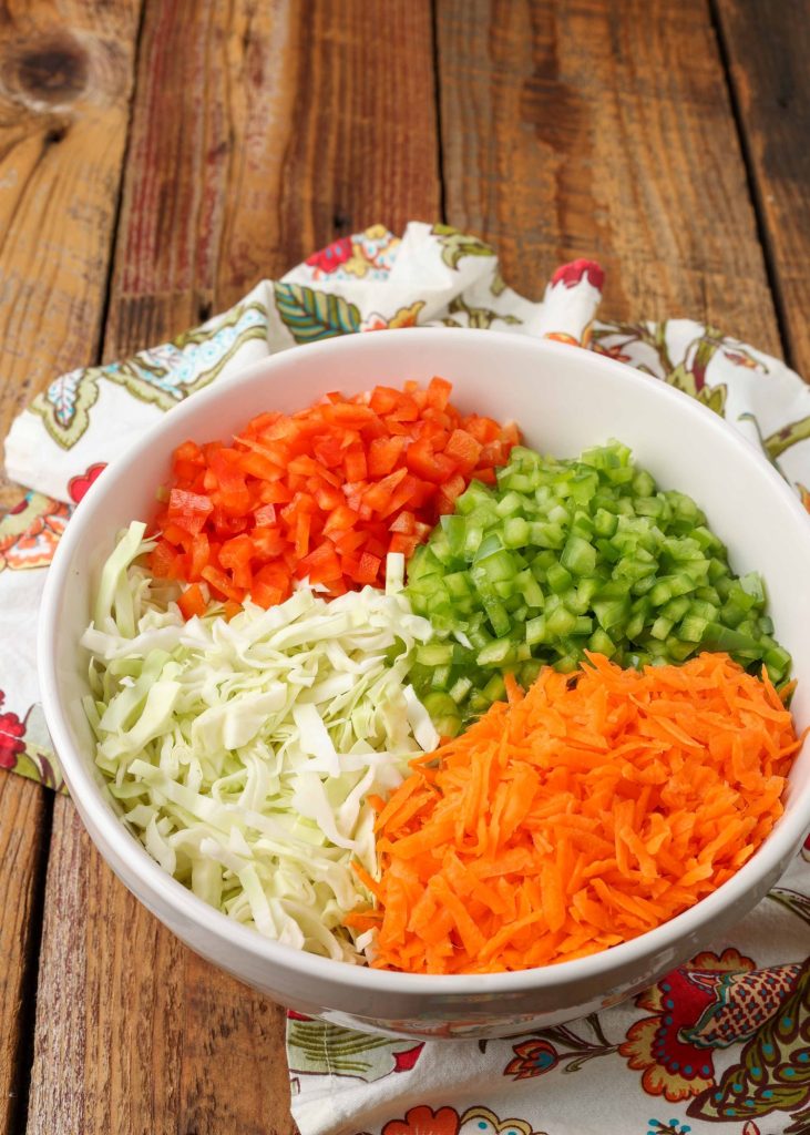cabbage, carrots, and bell peppers in mixing bowl