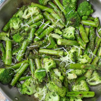 sauteed broccoli with asparagus topped with parmesan in stainless pan