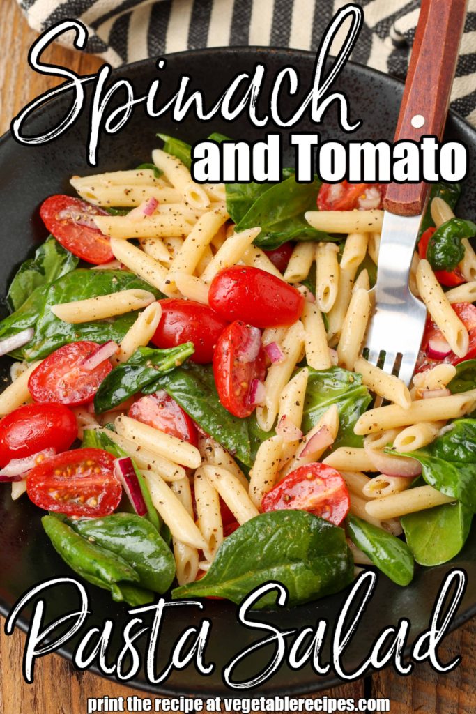 pasta salad with tomatoes and spinach in bowl with fork