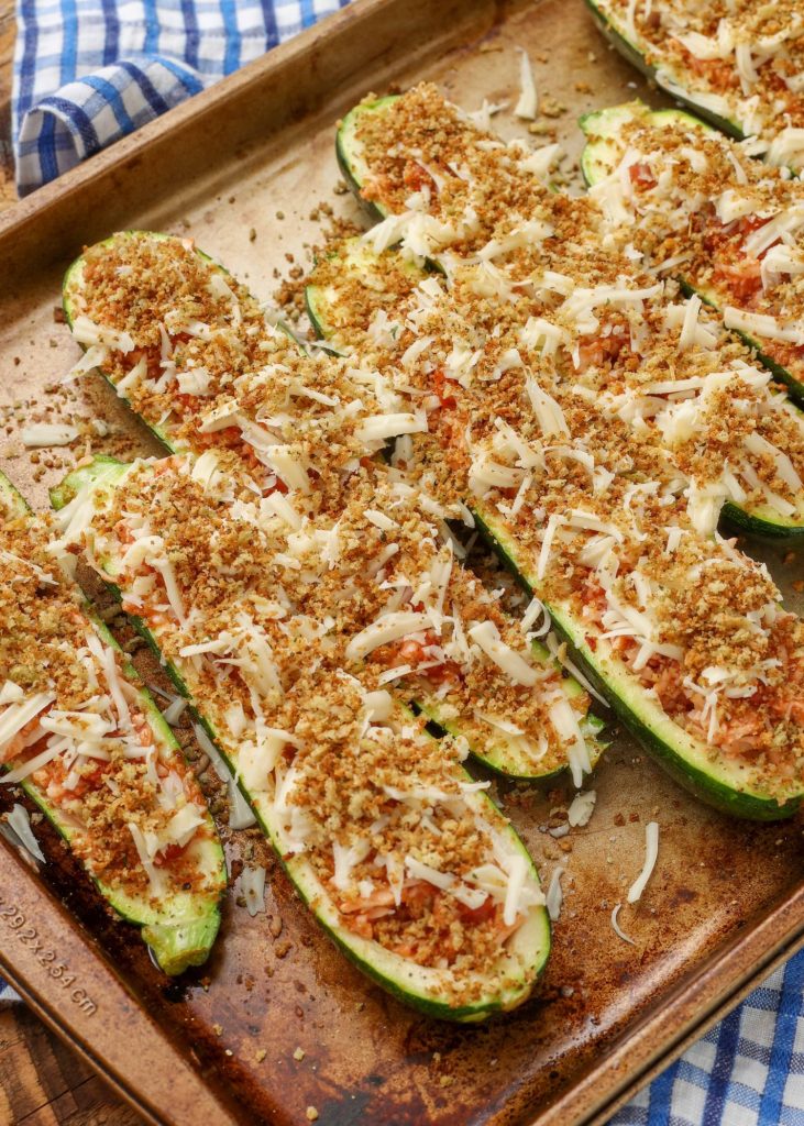 parmesan chicken zucchini boats are completely ready for their final stint in the oven, topped with bread crumbs and shredded mozzarella