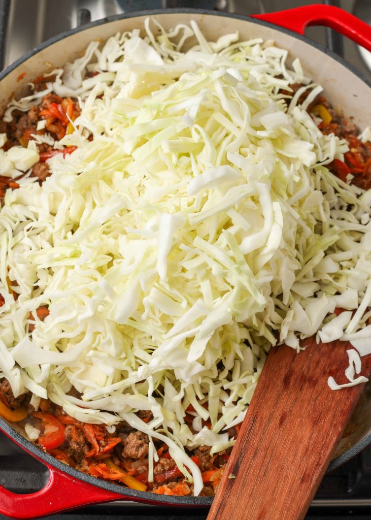 shredded cabbage has been placed atop the rest of the cooked ingredients in the skillet