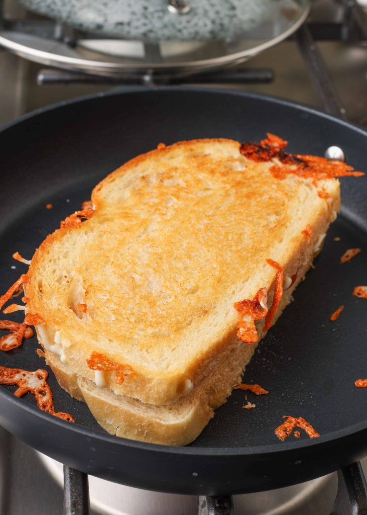 the grilled cheese has been flipped in this process shot with a non-stick pan