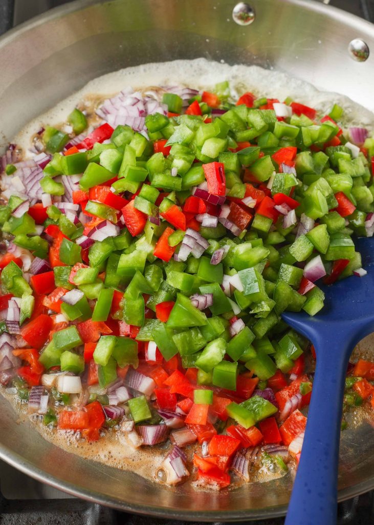 bell peppers, jalapenos, and onions have been added to a metal skillet