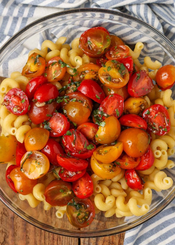 a top down shot of a bowl of tomato pasta salad