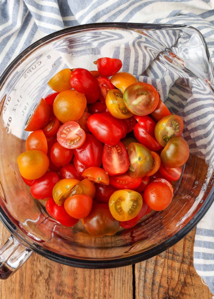 a pyrex measuring cup full of halved tomatoes