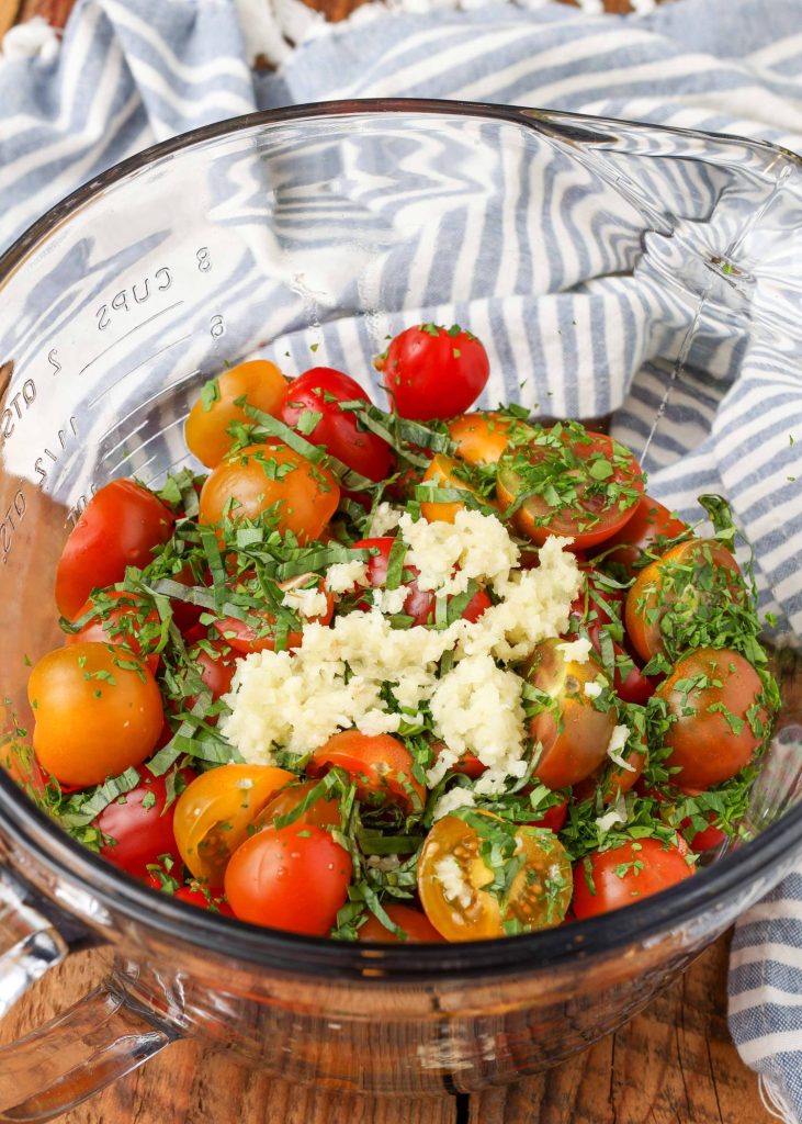 a glass bowl with halved tomatoes, on top of which have been added seasoings