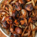 a close up shot of halved mushrooms and sliced onions after being sauteed