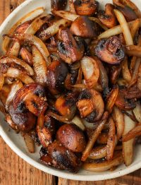 a close up shot of halved mushrooms and sliced onions after being sauteed