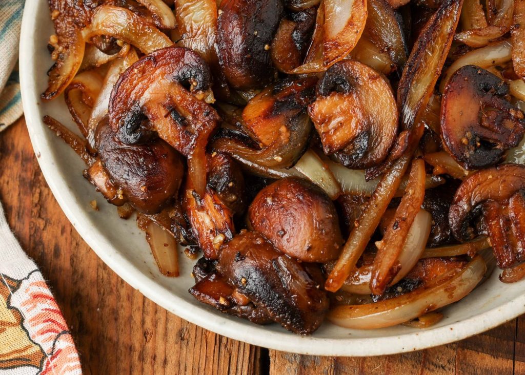 a top down photo of a white bowl filled with sauteed mushrooms and onions