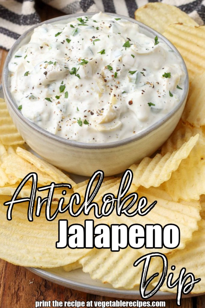 a small glass bowl of artichoke jalapeno dip beside a pile of ruffled potato chips on a plate