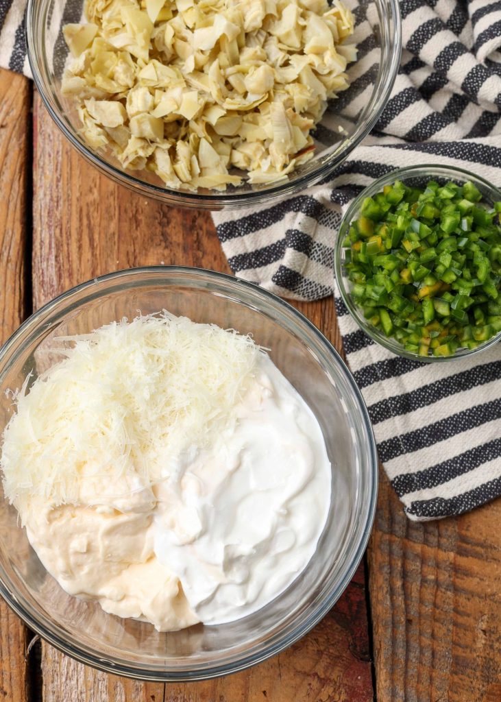 ingredients for artichoke jalapeno dip have been placed in glass bowls prior to combining